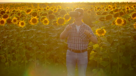 A-man-stands-on-the-field-with-sunflowers-and-works-with-virtual-reality-glasses.-He-tests-modern-technology-for-scientific-development.